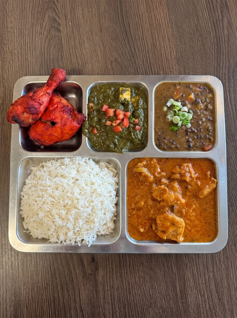 Indian thali with tandoori chicken, palak paneer, dal makhani, butter chicken, and basmati rice.